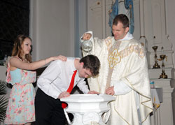 Father Johnathan Meyer, pastor of All Saints Parish in Dearborn County, baptizes Evan Fischer during the parish’s Easter Vigil Mass at St. Martin Church in Yorkville on April 4, while Holly Lattire, Evan’s sponsor, places her hand on his shoulder. (Submitted photo)