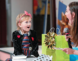 In this 2019 photo, a girl reacts with surprise as she hears about the gift she is receiving from the Little Wish Foundation, a non-profit foundation that Liz Niemiec, right, started when she was 16 to grant wishes to children and teenagers battling cancer. (Submitted photo)