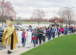 Father Ben Muhlenkamp leads Our Lady of Mt. Carmel students in a Eucharistic procession to the school gym after celebrating Mass in the church on April 1. (Photo by Caroline B. Mooney)