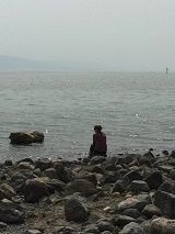 woman sitting by the edge of the sea of galilee