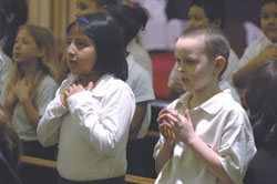 From left, Sandra Compus, a third-grader at St. Anthony School in Indianapolis, and Brandon Duke, a kindergartner at the school, sing a song and make sign language gestures during a March 12 Mass at St. Anthony Church in honor of St. Theodora.