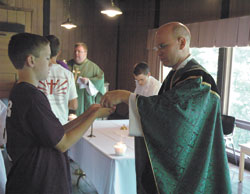 Grady Gaynor, a member of Our Lady of Mount Carmel Parish in Carmel, Ind., in the Lafayette Diocese, receives Communion from Father Robert Hausladen on June 15, 2006, during the first Bishop Bruté Days held at Bradford Woods Retreat Center near Martinsville.
