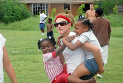 Marianne Krueger, a high school senior and member of St. Paul Parish in Tell City, carries two young girls in a park in St. Bernard Parish, La., during a June 25-29 volunteer trip sponsored by her parish. The 22 teenagers and eight adult leaders were cleaning up the park when the children arrived from a nearby daycare center. (Submitted photo) 