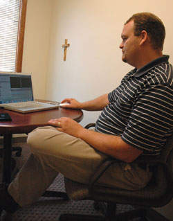 Jonathan Chamblee works on a video editing program on his laptop computer in his office at Holy Name of Jesus Parish in Beech Grove, where he serves as coordinator of religious education.
