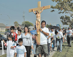 St. Mary parishioner Roberto Aguayo of Indianapolis carries a large wooden crucifix and leads pro-life supporters along West 86th Street in Indianapolis on Sept. 23 while his wife, Patricia, in the ninth month of her pregnancy, walks beside him with their children, Roberto, Andrea and Ricardo. The Aguayos’ baby, Rolando, was born on Sept. 29. Dozens of pro-life supporters prayed the rosary for an end to abortion during the two-mile march to the Planned Parenthood center for a prayer vigil.