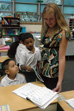 Crystal Barthel, a third-grade teacher at St. Philip Neri School in Indianapolis, reviews the work of Carlos Caldera, left. Fernando Zuniga, second from left, waits to talk to Barthel. Barthel was in the first class of recipients of scholarships from the CHOICE Charitable Trust in 1991 when she was a student at Holy Cross Central School in Indianapolis. (Photo by Sean Gallagher)	