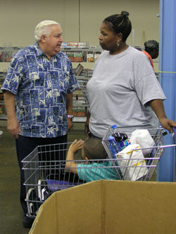 Jake Asher, left, takes the time to talk with Jenean Hoskin and her grandson, Daniel, sitting in the shopping cart. As the president of the Indianapolis Council of the Society of St. Vincent de Paul, Asher supervises the Pratt-Quigley Center which offers free food, medical care and legal assistance to people in need.