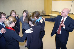 Marian College speech and debate coach the Rev. George LaMaster, right, prays with his team before a tournament at Ball State University in Muncie, Ind., in October 2007. “I never thought I’d have a speech team where I could start a competition with a prayer. That’s a wonderful thing,” LaMaster said. “It gives a character to the whole experience. It holds the competition in perspective.” (Submitted photo)	