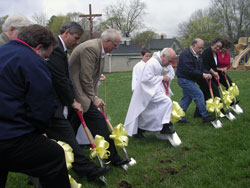 St. Joseph parishioners join Father Daniel Atkins, pastor, at the groundbreaking for a long-awaited parish hall in Corydon on April 13. The group who broke ground included project manager Joe Shireman, left; architect Larry Timperman (hidden); fundraising committee members Ron Casabella and Mike Bennett; Father Atkins; parish finance chairman Ed Hoehn; parish council president Teresa King; and Heidi Imberi, the principal of St. Joseph School. (Photo by Patricia Happel Cornwell) 