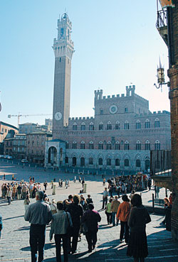 Tourists and townspeople gather at Siena’s Piazza del Campo, where its famous horse race, the Palio, is run twice a year. The Italian city’s medieval town hall, the Palazzo Pubblico, dominates the plaza with its tall clock tower. (Photo by Sean Gallagher)
