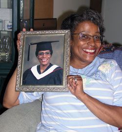 Vera Crowl doubles the pleasure of her smile as she poses with a picture of herself in her cap and gown. After 30 years of struggling with alcohol and drug addiction, Crowl returned to college after God told her that he wanted her to help others. (Photo by John Shaughnessy)