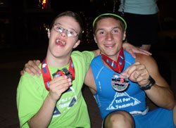 Tommy Steiner, left, savors a moment to remember with his friend and coach, Jimmie Guilfoyle. The friends, who met at Our Lady of Providence Jr./Sr. High School in Clarksville, proudly display their medals from the Louisville Ironman competition. Guilfoyle dedicated his participation in the Ironman to raise funds for an association that helps Tommy and other people who have Down syndrome. (Submitted photo) 