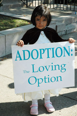 Three-year-old Iranelly Madrigal holds a pro-life sign promoting adoption in front of the SS. Peter and Paul Cathedral rectory in Indianapolis during the Central Indiana Life Chain on Oct. 5 as part of national Respect Life Sunday observances. She is the daughter of St. Bartholomew parishioner Rocio Sanchez of Columbus. (Photo by Mary Ann Wyand) 