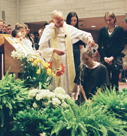 Dominican Father Robert Keller, pastor of the St. Paul Catholic Center in Bloomington, baptizes Hillary Brooks, a senior at Indiana University in Bloomington, during the parish’s Easter Vigil on April 11. (Submitted photo) 