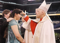 Cardinal Francis E. George of Chicago confirms Alisha Webber, a member of Holy Family Parish in Oldenburg, during the May 3 Mass at Lucas Oil Stadium in Indianapolis that celebrated the 175th anniversary of the Archdiocese of Indianapolis. (Photo by Sean Gallagher) 