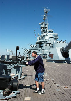 St. Michael the Archangel parishioner Dan Roth of Plymouth, Ind., in the Fort Wayne-South Bend Diocese, examines a large gun on the deck of the USS Alabama, which is moored along the shore at Mobile, Ala., and serves as a naval museum. His grandfather, Seaman First Class Paul L. Travis, served in the U.S. Navy on board the battleship for three years during World War II. (Photo by Mary Ann Wyand) 