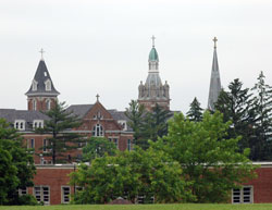 The spires of Holy Family Church and the motherhouse of the Congregation of the Sisters of the Third Order of St. Francis rise up over the trees of historic Oldenburg. The southeastern Indiana town serves as the starting and ending point of the two loops of the “Vatican Ride” in which bicyclists can view several parish churches in Franklin County. (File photo by Mary Ann Wyand) 