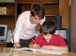 Volunteer Janie Kabrick helps William Kathman, a second-grade student at St. Charles Borromeo School in Bloomington, with a handwriting lesson on April 1. Kabrick is an occupational therapist who works with first- and second-graders one day a week at the school. (Photo by Mike Krokos) 