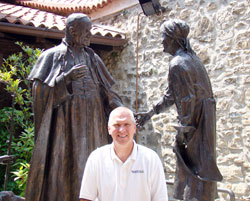 To mark his 25 years at Roncalli High School in Indianapolis, principal Chuck Weisenbach traveled to Italy this summer to learn more about the life of Angelo Roncalli—the peasant boy who grew up to become Pope John XXIII. Weisenbach stands near a bronzed statue of Pope John XXIII that was erected in front of the home where Angelo Roncalli was born. (Submitted photo)