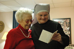Sister Margaret Banar, a member of the international Little Sisters of the Poor congregation, looks at photographs with St. Augustine Home for the Aged resident Beatrice Spurgeon of Indianapolis in this Dec. 22, 2007, file photo. (File photo by Mary Ann Wyand)