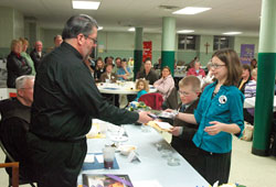 Father Christopher Craig, pastor of St. Joseph Parish in Shelbyville, receives gifts from first-grader Dakota Sosbe, left, and sixth-grader Makayla Schacht, both participants in St. Joseph’s religious education program, during a Year for Priests event on March 6 at the Batesville Deanery parish. (Photo by Sean Gallagher)