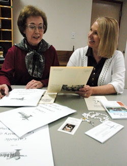 Christ the King Parish staff members Rose Sterger, left, and Melissa Buechler of Indianapolis prepare new member welcome packets that include a rosary, holy card of St. Theodora Guérin, Mass schedule and other parish information to help newcomers connect to the faith community. (Photo by Mary Ann Wyand)