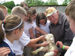 Students from St. Roch School in Indianapolis surround 92-year-old Art Huser and one of the sheep that he raises and shepherds at his 10-acre home on the south side of the city. St. Roch teacher Dick Gallamore refers to Huser as “a modern-day St. Francis of Assisi.” (Submitted photo)