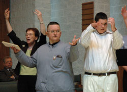 St. Mark the Evangelist parishioner Chuck Ward of Indianapolis, center, sings and uses hand gestures during the archdiocesan SPRED Mass for Special Religious Development participants on April 27, 2008, at St. Mark the Evangelist Church. Joining him as music ministers for the liturgy are, left, St. Mark parishioner and volunteer catechist Jean Milharcic and, right, SPRED participant Nick Shewman from Nativity of Our Lord Jesus Christ Parish in Indianapolis. For more information about the SPRED program, call Ken Ogorek at 317-236-1446 or 800-382-9836, ext. 1446. (File photo by Mary Ann Wyand)