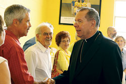 Archbishop Daniel M. Buechlein, right, shakes hands with Brett Sciarra, left, a member of St. Ambrose Parish in Seymour, on June 27 at the parish. Fred Sciarra, second from left, his father, and Arlene Calmer look on. (Photo by Jamie Marshall/Marshall Memories)