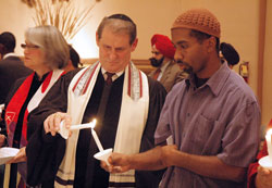 Giora Sharon, center, the cantor and choir director for the Congregation Beth-El Zedeck synagogue in Indianapolis, lights a candle from the candle of Shakoor Siddeeq, the treasurer of the Nur Allah Islamic Center in Indianapolis, during the 11th annual Interfaith Thanksgiving Service on Nov. 23 at SS. Peter and Paul Cathedral in Indianapolis. (Photo by Sean Gallagher)