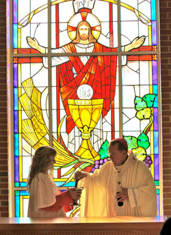 Roncalli High School freshman Danielle Babb, a member of St. Roch Parish in Indianapolis, assists Archbishop Daniel M. Buechlein as an altar server during the dedication Mass for the new Chapel of the Sacred Heart on Dec. 7 at Roncalli High School in Indianapolis. (Submitted photo/Kristen West)