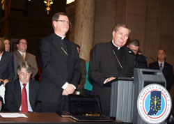 Archbishop Daniel M. Buechlein, right, speaks during a Feb. 9 ceremony at the Indiana Statehouse in Indianapolis during which he, Bishop Timothy L. Doherty of Lafayette, center, Indiana Attorney General Greg Zoeller, left, and other state religious, government and business leaders signed the Indiana Compact, an agreement that calls for immigration reform to happen at the federal and not state level. (Submitted photo by Charles Schisla)