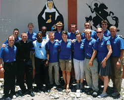 Members of a young adult mission team from the Archdiocese of Indianapolis traveled to Haiti on May 10-17, 2010, with Father Rick Nagel. Posing for a photo in front of images of St. Theodora Guérin and St. George in Bassin-Bleu, Haiti, last spring are, front row, from left, seminarian Tyler Tenbarge, Father Nagel, Father Jean Gregory Jeudy from Haiti, Matt Johnson, Anne Marie Brummer, Missy Brassie, seminarian Tony Hollowell, Erica Heinekamp and Scott Goley, and back row, from left, Scott Lutgring, Steve Rogers, Father Rodolphe Balthazar from Haiti, Michael Conner, Michael Gramke, Robert Barnell and Joe Pederson. (Submitted photo)