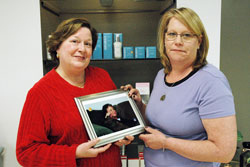 Teresa Bryan, left, and Carolyn Smith hold a photo of their sister, Ruth Anne Arajuo, who died of cancer in 2005. Arajuo is the inspiration for Smith’s decision to provide free weekly services to cancer patients at her Indianapolis salon that offers pedicures, manicures, facials and massages. (Photo by John Shaughnessy)
