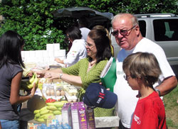 As the founder of a grassroots group that helps the poor, Tim Hahn, second from right, has learned that his efforts to help others work best when he puts his trust in God. Here, Hahn stands between 10-year-old Alexander Simons and Amy Moore as people in line select the food they want for their families in July of 2010. (File photo by John Shaughnessy)
