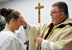 Heather, who is incarcerated at the Indiana Women’s Prison in Indianapolis, receives the sacrament of confirmation from Father Robert Robeson on Easter in a chapel at the state correctional facility. Two women were baptized and five women received the sacraments of confirmation and the Eucharist during the April 24 liturgy. (Photo by Mary Ann Wyand)