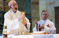 In this 2006 file photo, retired Father Herman Lutz, left, elevates a chalice during a Mass celebrated in the chapel of St. Paul Hermitage in Beech Grove. Concelebrating at the Mass was Father Henry Brown, right, who died in 2009. (File photo by Sean Gallagher)