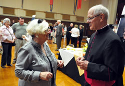 Msgr. Paul Richart, right, pastor of St. Paul Parish in Sellersburg, greets Joyce Gambrall, a member of the New Albany Deanery faith community, during an Aug. 14 reception at the Archbishop O’Meara Catholic Center Assembly Hall in Indianapolis after he was honored as a monsignor by Bishop Christopher J. Coyne, auxiliary bishop and vicar general, during an Evening Prayer liturgy at SS. Peter and Paul Cathedral. Msgr. Richart served as an Air Force chaplain for 29 years and achieved the rank of colonel. (Photo by Sean Gallagher)
