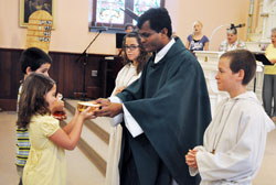 Father Sengole Thomas Gnagnaraj receives offertory gifts from Luke and Elizabeth Geraci during a Sept. 4 Mass at St. John the Baptist Church in Dover. He is assisted by altar servers Olivia and Glenn Geraci, who are Luke and Elizabeth’s siblings. Father is associate pastor of the parishes of St. John the Baptist in Dover, St. Joseph in St. Leon, St. Martin in Yorkville and St. Paul in New Alsace. (Photo by Sean Gallagher)