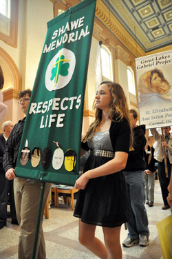Myles Hesse, left, and Hannah Miller, both freshmen at Father Michael Shawe Memorial Jr./Sr. High School in Madison, carry a banner from their school at the start of the annual archdiocesan Respect Life Sunday Mass on Oct. 2 at SS. Peter and Paul Cathedral in Indianapolis. Myles and Hannah are members of Prince of Peace Parish in Madison. (Photo by Sean Gallagher)