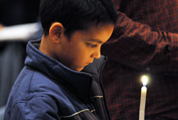 Nine-year-old Evett Singh, a member of The Salvage Yard Christian Church in Indianapolis, watches the flame burning on his candle during the Interfaith Prayer Service on Nov. 22 at SS. Peter and Paul Cathedral in Indianapolis. He was among many children who participated in the 12th annual prayer service with their parents. (Photo by Mary Ann Garber)