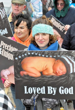 Elizabeth Jamison, center, associate director of vocations for the archdiocese, and more than 400 other pro-life supporters from parishes in central and southern Indiana brave the cold during the archdiocese’s second annual Local Solemn Observance and Respect Life March on Jan. 23 in Indianapolis to peacefully protest the 39th anniversary of Roe v. Wade, the tragic Supreme Court decision that legalized abortion in the United States during all nine months of pregnancy. (Photo by Mary Ann Garber)