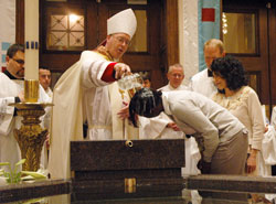 Bishop Christopher J. Coyne baptizes Tomiko Whitaker during the celebration of the Easter Vigil on April 23, 2011, at SS. Peter and Paul Cathedral in Indianapolis. Jerry Galooley, right, served as Whitaker’s sponsor. (File photo by Sean Gallagher)