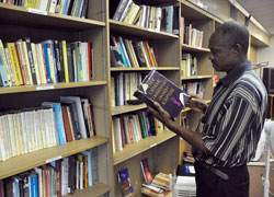 Alex Ogbuh, a maintenance worker at St. Rita Parish in Indianapolis, looks at a book on Sept. 17 in the parish’s library. In 2011, St. Rita Pasrish received a Growth and Expansion grant from the archdiocese to expand the holdings of the library. Recent changes to the application process for archdiocesan grants will make more funds available more often to parishes across central and southern Indiana. (Photo by Sean Gallagher)