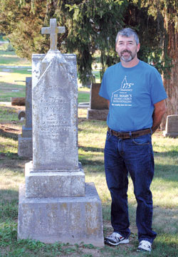 Scott Thralls, a member of St. Mary-of-the-Woods Parish in St. Mary-of-the-Woods, stands next to the tombstone of Joseph Thralls, his great-great-great-grandfather, on Aug. 30. Joseph Thralls donated the land on which St. Mary-of-the-Woods Parish originally stood. It later became the grounds for the motherhouse of the Sisters of Providence of Saint Mary-of-the-Woods. The Terre Haute Deanery parish is celebrating the 175th anniversary of its founding this year. (Submitted photo)