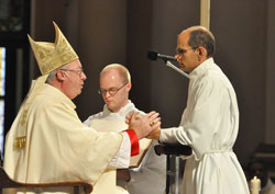 Deacon candidate Russell Woodard ritually places his hands in the hands of Bishop Christopher J. Coyne, apostolic administrator, during a June 23 Mass at SS. Peter and Paul Cathedral in Indianapolis. During the Mass, Woodard and 15 other men were ordained as permanent deacons for the Archdiocese of Indianapolis. (File photo by Sean Gallagher)