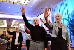 Franciscan Sisters Rita Vukovic, from left, Jan Kroeger and Jacquelyn McCracken raise their hands as they sing “The Blessing of St. Clare” with other sisters at the conclusion of Marian University’s 75th anniversary awards dinner and celebration on Oct. 19 in downtown Indianapolis. (Photo by Mary Ann Garber)