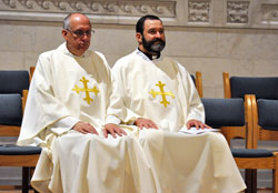 Father Steven Giannini, left, and Father Aaron Pfaff sit after Communion during a Nov. 7 Mass at SS. Peter and Paul Cathedral in Indianapolis. They are wearing chasubles taken from a set of 300 that have been made by The House of Hansen in Chicago for the archdiocese to use during major archdiocesan liturgies. They will be used on a large scale for the first time at the Dec. 3 Mass at the cathedral during which Archbishop Joseph W. Tobin will be installed as the sixth archbishop of Indianapolis. (Photo by Sean Gallagher)