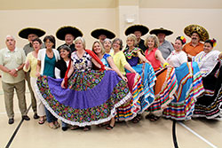 Along with native Mexican dancers, women participating in the archdiocese’s first-ever Spanish immersion program dress in traditional folkloric dresses while the men wear sombreros with Father John McCaslin, third from left in the back row, and Franciscan Brother Moises Gutierrez, far right in the back row, during a break in the program held at Padua Academy in Indianapolis on June 7. (Submitted photo)