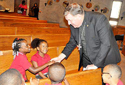 Archbishop Joseph W. Tobin greets Project SAFE students Jayonna Zinerman, left, and Mireya Benjamin on Oct. 3 at St. Andrew the Apostle Church in Indianapolis. Project SAFE (St. Andrew Faith Enrichment) is an afterschool religious education program sponsored by St. Andrew Parish for students of Andrew Academy, a public charter operated by the Archdiocese of Indianapolis on the parish’s campus. (Photo by Sean Gallagher)